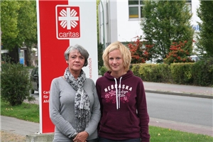 Auf dem Foto stehen Fr. Theissen-Beckmung und Frau Pohlmann vor dem Caritas-Banner